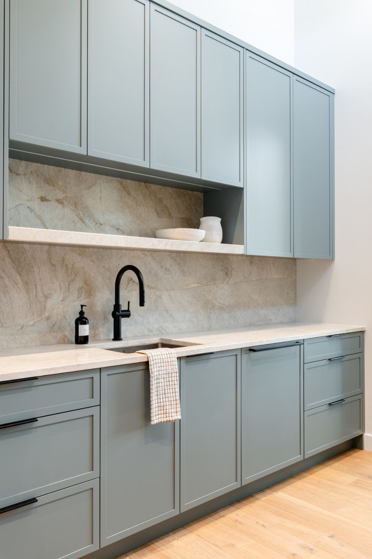 a kitchen with gray cabinets and white counter tops