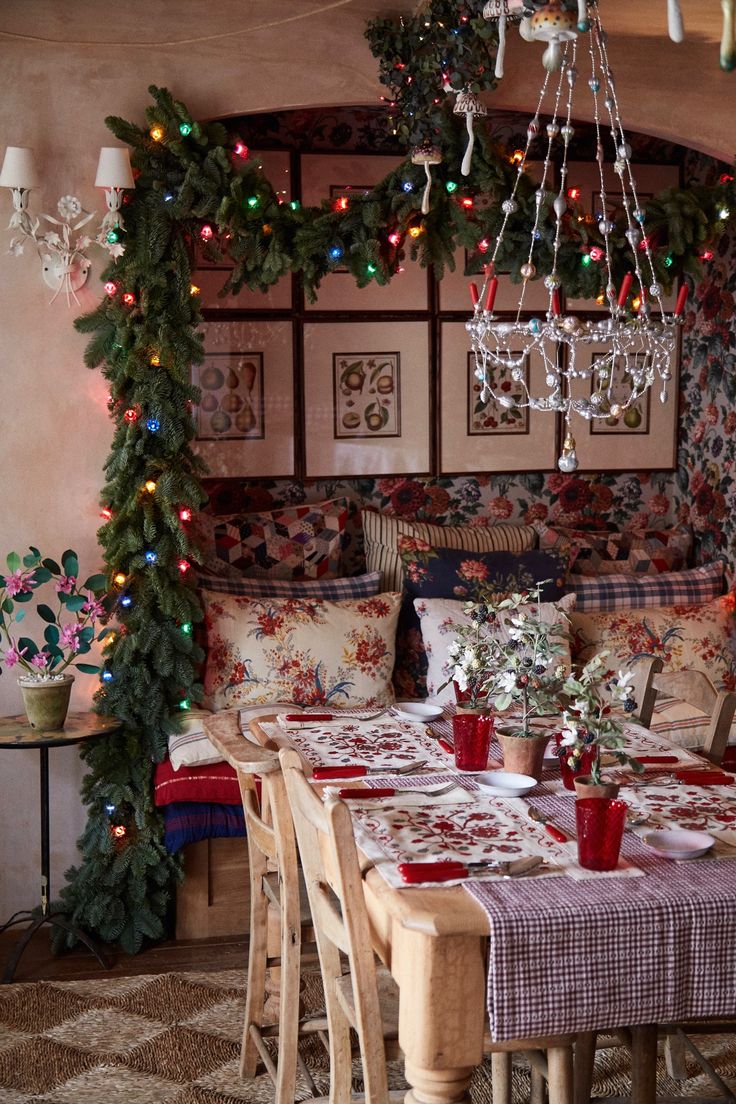 a dining room table with christmas decorations on the wall and lights hanging from the ceiling