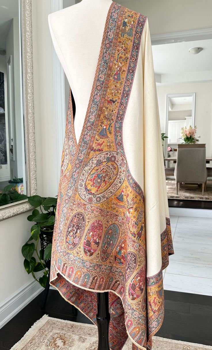 A Kani Doli Barat At shawl is a regal and exquisite piece of traditional Kashmiri craftsmanship. Woven using the intricate Kani weaving technique, this shawl showcases a finely detailed pattern of doli barat, symbolizing the traditional wedding processions. The shawl is crafted from luxurious fine wool, renowned for its softness and warmth. The intricate designs are created using small, colorful threads, meticulously woven into the fabric. The Kani Doli Bar At shawl is not just a fashion accesso Luxury Festive Scarves With Resham Embroidery, Luxury Katan Silk Pashmina Shawl With Cutdana, Luxury Woven Motifs Shawl For Women, Luxury Traditional Pashmina Shawl, Luxury Handloom Shawl, Luxury Chanderi Shawl With Traditional Patterns, Luxury Traditional Pashmina Shawl For Wedding, Traditional Luxury Scarves With Intricate Embroidery, Luxury Chikankari Embroidery Shawl