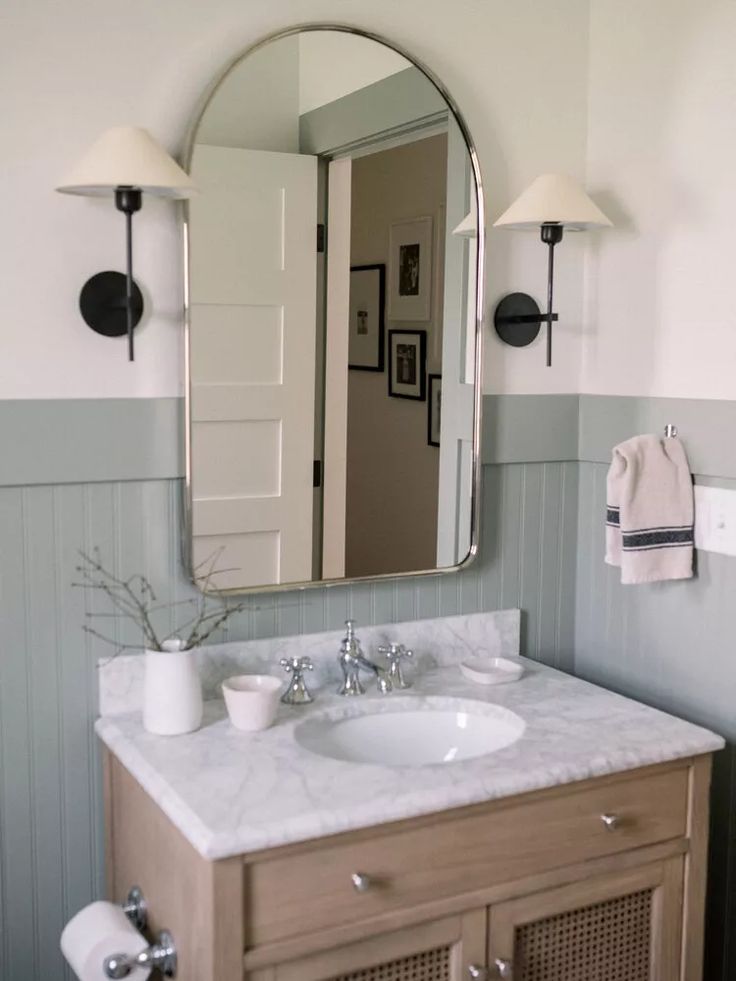 a bathroom sink with a mirror above it and two lights on the wall next to it