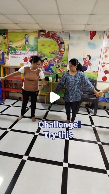 two women are dancing on a checkered floor in front of children's artwork