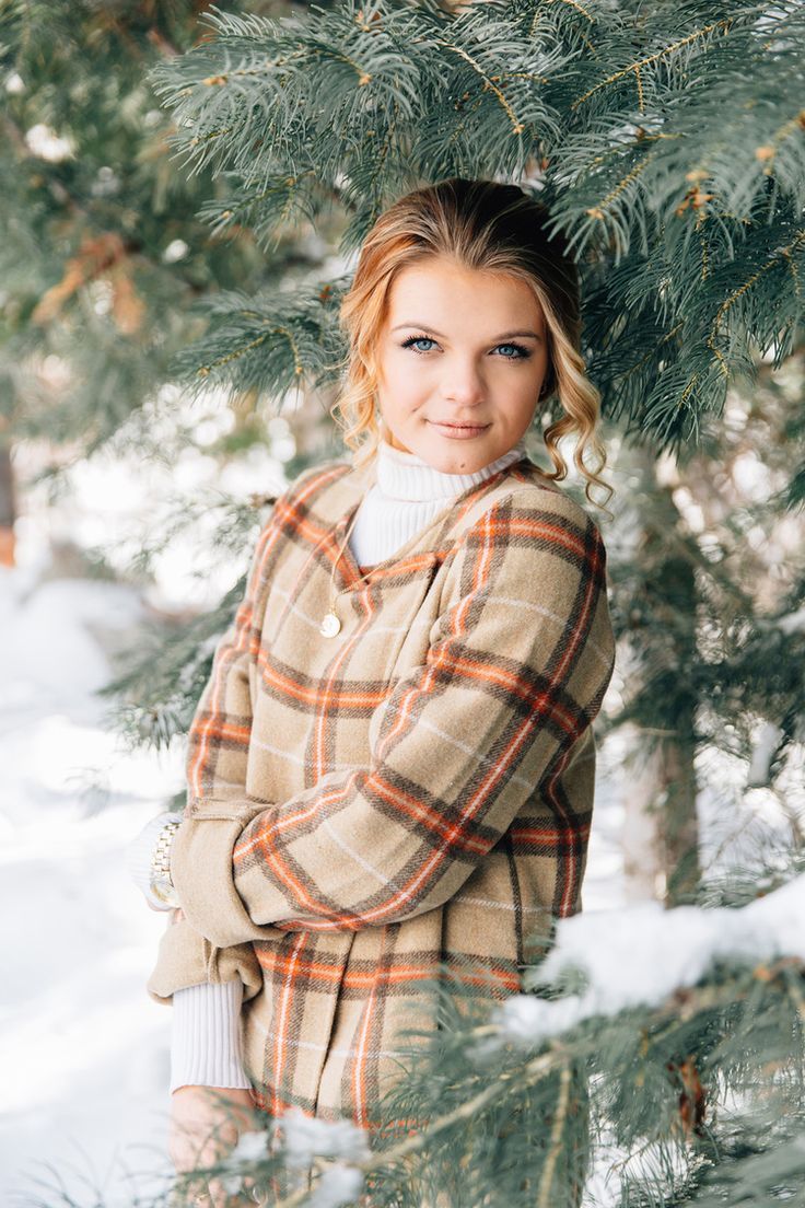 a woman standing in front of a pine tree with her arms wrapped around the branches