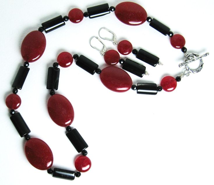 Red mountain jade, black tourmaline necklace (19 inches) with a sterling silver toggle clasp. The matching earrings are on sterling silver leverbacks with a 1.4-inch drop. Red mountain jade is a gemstone of color-enhanced high-grade dolomite marble from Asia. Both red mountain jade and tourmaline are gemstones. There are two shapes of red mountain jade beads: flattened ovals (25 x 18 mm) and flattened round beads (11 mm in diameter).The black tourmaline beads are flattened cylinders (16 x 9 mm).There are also 4 mm black faceted beads in the necklace. Red mountain jade is the gemstone of October-November. Tourmaline is a birthstone of October. Black Jade Jewelry With Natural Stones, Fine Jewelry Agate Gemstone, Oval Jade Gemstone Beads Jewelry, Single Strand Agate Jewelry Gift, Elegant Sterling Silver Clasp Pendant Jewelry, Elegant Oval Gemstone Beads Jewelry, Elegant Formal Agate Jewelry, Classic Jade Gemstone Beads Jewelry, Red Agate Jewelry With Natural Stones