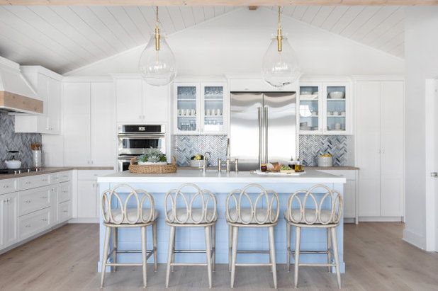 a kitchen with white cabinets and light blue countertops, four bar stools in front of the island