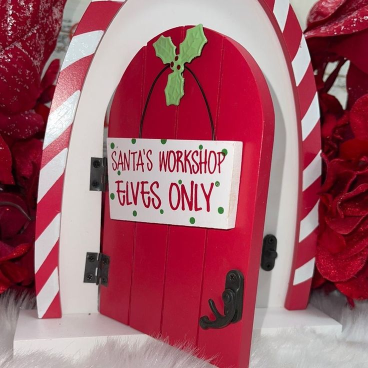 a red and white christmas door with santa's workshop elves only sign on it