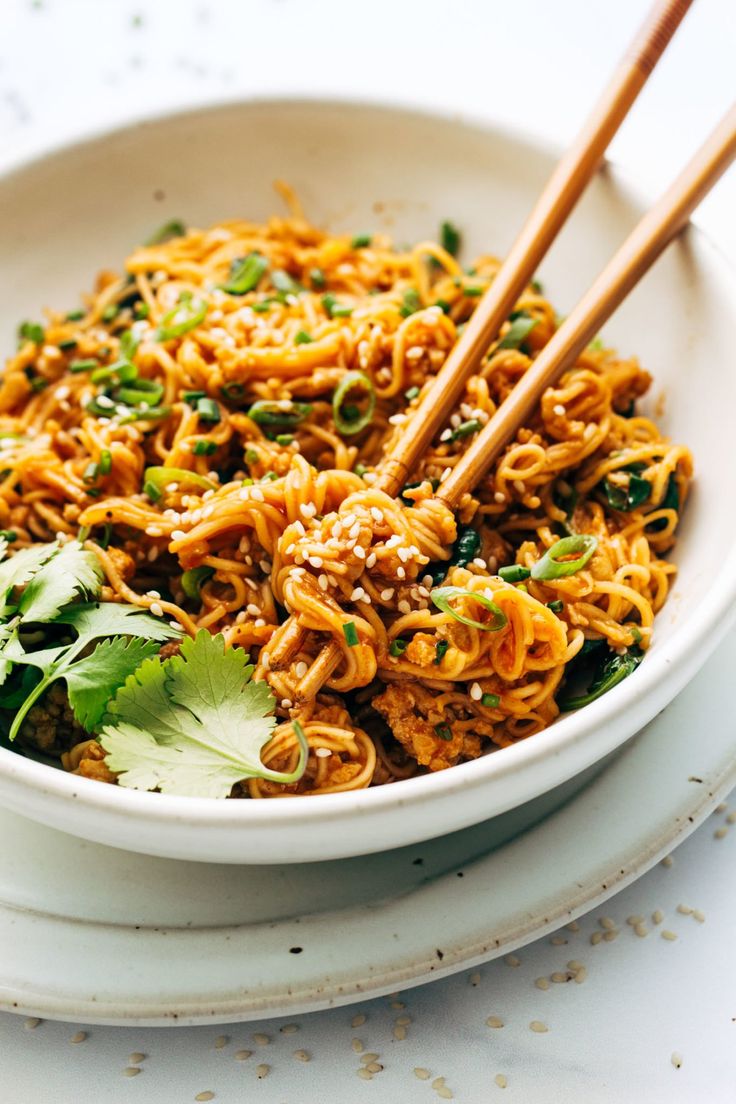 a white bowl filled with noodles and chopsticks