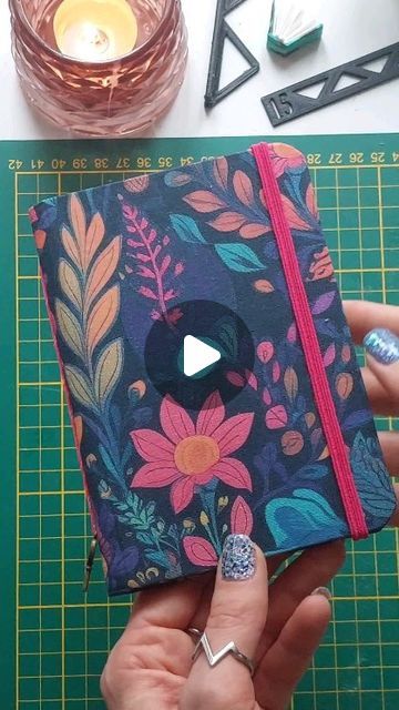 a person holding a notebook with flowers on it and a video playing in the background