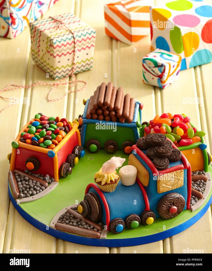 a cake shaped like a train with lots of candy on the tracks and candies