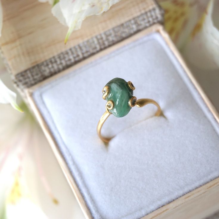 Dark green and gold create an emerald ring that sings with elegance and stands for bravery. The adjustable ring easily fits various ring sizes. The 14k gold filled metal setting creates a long-lasting and hypoallergenic ring. Each handmade pair uses a three step adhering process to guarantee durability and quality, Hypoallergenic material guarantees no reaction when you wear them. As no raw stone is the same, each emerald ring has a slightly different shape and size guaranteeing uniqueness and i Adjustable 14k Gold Emerald Ring, Adjustable Green Emerald Ring For Wedding, Yellow Gold Emerald Jewelry, Heirloom Gold Jade Ring, Heirloom Jade Ring Jewelry, Heirloom Jade Ring In Gold, Gold Crystal Promise Ring For May Birthstone, Elegant Adjustable Gold Emerald Ring, Adjustable Gold Emerald Ring As Gift