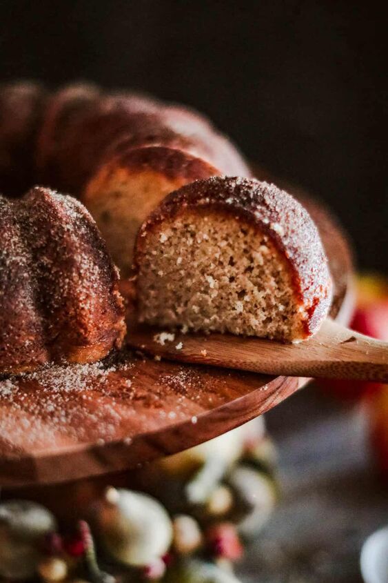 a bundt cake is cut into pieces and sitting on a wooden platter with an apple in the background