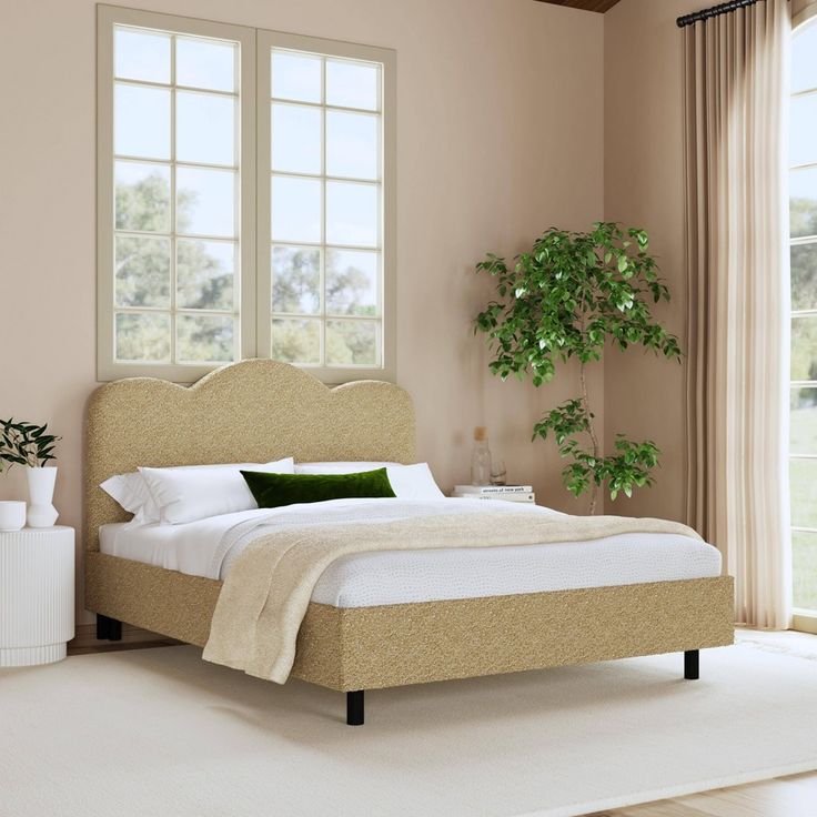 a bedroom with a large bed and two windows in it's corner, next to a potted plant on the floor