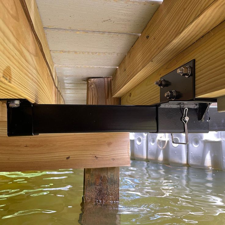 the underside of a wooden structure with metal brackets on it's sides and water below