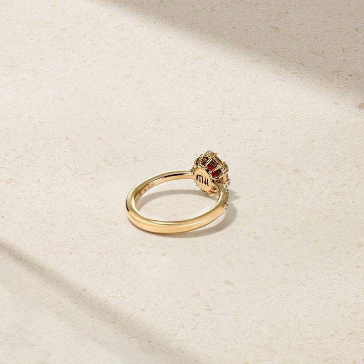 A glowing red ruby lays at the center of this meticulously crafted ring that's framed by a halo of twinkling round and baguette diamonds. Additional petite round diamonds sparkle along each end of the comfort fit shank to complete the look. Make this elegant and timeless adornment apart of your everyday jewelry rotation. Metal: 18kt Gold Ruby Weight: 0.60 ct. Round Diamond Weight: 0.25 ct. Baguette Diamond Weight: 0.22 ct. Measurements: 10.0 mm length *Please note that the listed ct. weights are Red Diamond Ring With Baguette Cut, Red Diamond Cluster Ring With Halo Setting, Red Diamond Baguette Cut Rings, Luxury Ruby Ring With Halo, Red Ruby Ring With Baguette Diamonds, Luxury Ruby Ring With Center Stone For Proposal, Formal Ruby Ring With Baguette Diamonds, Baguette Cut Ruby Ring With Diamond Center Stone, Baguette Cut Ruby Ring With Diamond