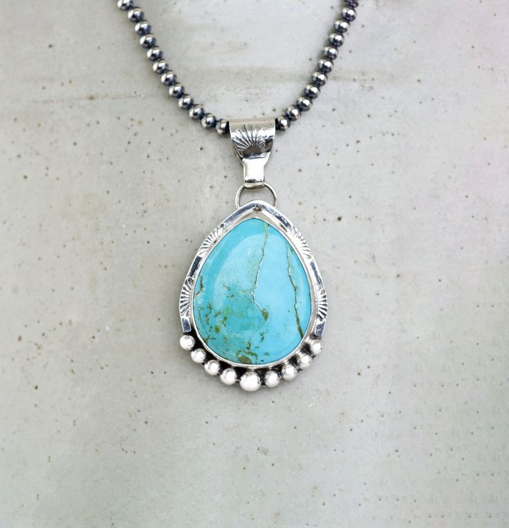 Kingman Sky Blue Turquoise Sterling Silver Necklace on your choice of chain. The setting is a chunky teardrop stone that is 27mm x 22mm and in a Bezel setting. The 925 Sterling Silver has been lightly oxidized.  Your choice of an 18" 3mm Navajo Pearls or 18" Silver Chain with Lobster clasp This cool necklace features a chunky, pear shaped turquoise gemstone with a detailed setting. The soothing hue of the turquoise brings out a southwest style vibe, while the silver accents add a touch of elegan Turquoise Teardrop Spiritual Jewelry, Spiritual Teardrop Turquoise Jewelry, Teardrop Turquoise Jewelry With Natural Stones, Turquoise Teardrop Natural Stone Jewelry, Blue Turquoise Necklace With Large Teardrop Stone, Unique Turquoise Teardrop Pendant Necklace, Unique Turquoise Teardrop Pendant Jewelry, Bohemian Teardrop Turquoise Necklace Nickel Free, Turquoise Teardrop Pendant Necklace With Large Stone