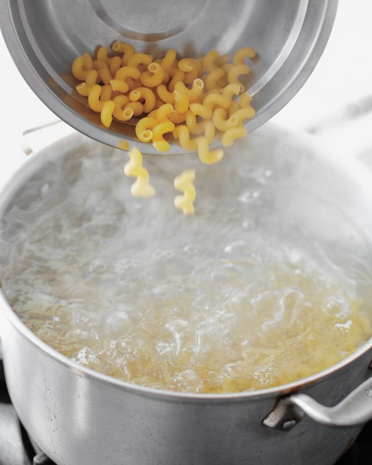 a pot filled with some kind of pasta being stirred by a ladle on the stove