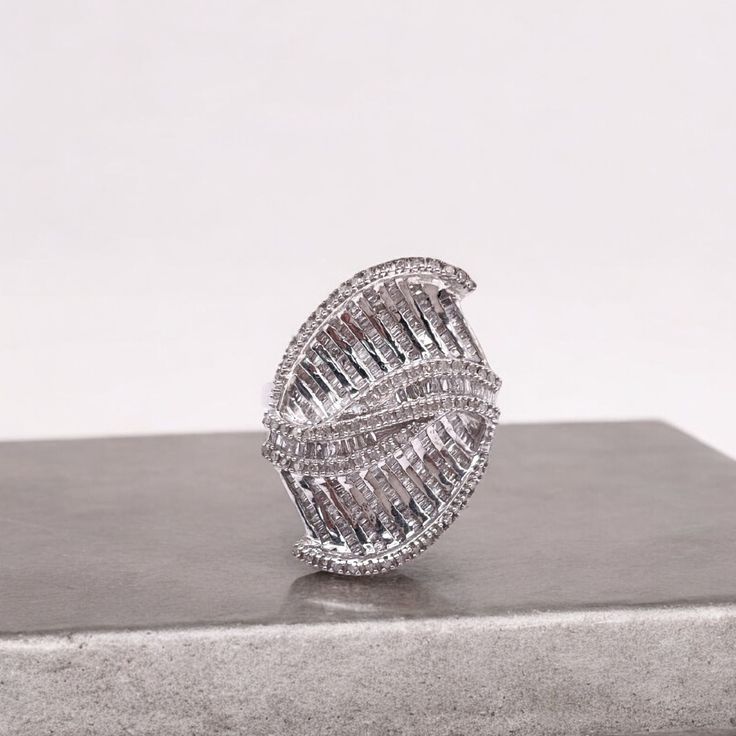 a large diamond ring sitting on top of a metal box next to a white wall