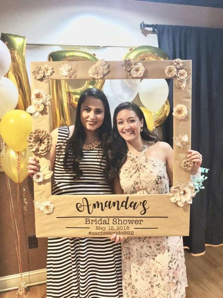 two women standing next to each other in front of a wooden sign that says annnda's bridal shower