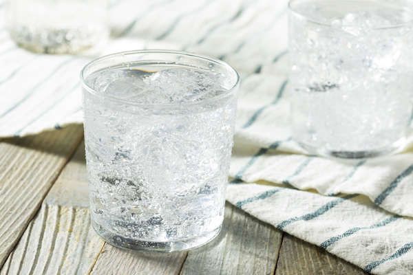 two glasses filled with water sitting on top of a wooden table next to a towel