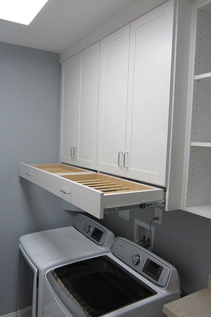 a washer and dryer in a small room with white cabinets on the wall