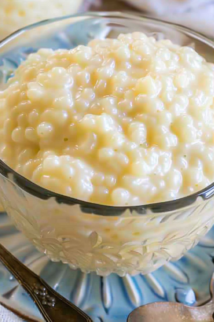 a glass bowl filled with macaroni and cheese on top of a blue plate