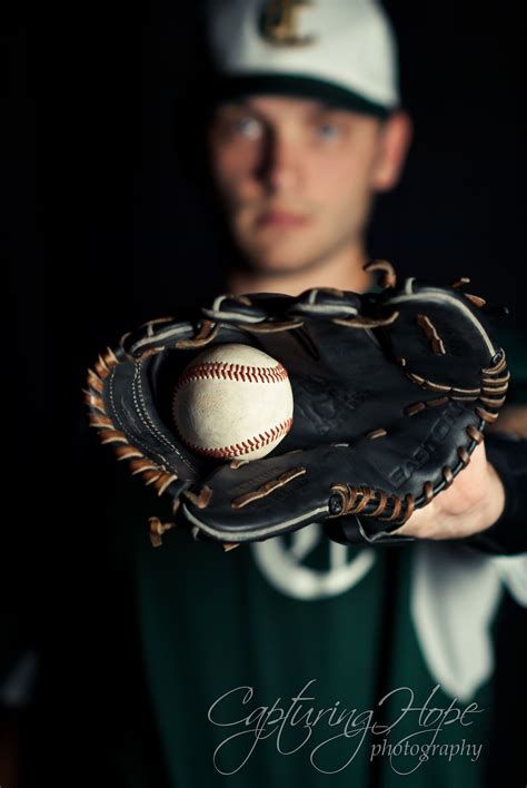 a baseball player is holding a ball in his mitt while wearing a green and white uniform