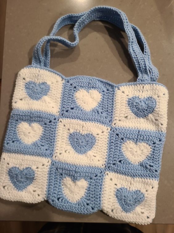 a crocheted blue and white purse with hearts