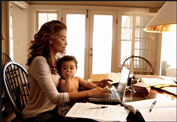 a woman sitting at a table with a child on her lap using a laptop computer