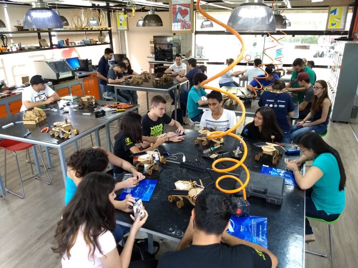 a group of people sitting around a table working on projectors in a room filled with tables and chairs