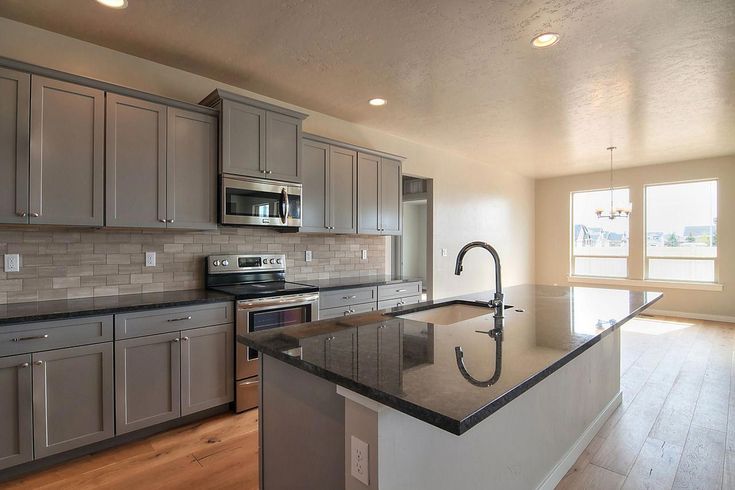 an empty kitchen with stainless steel appliances and granite counter tops, along with hardwood flooring