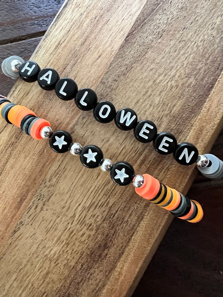 two halloween beaded bracelets sitting on top of a wooden table