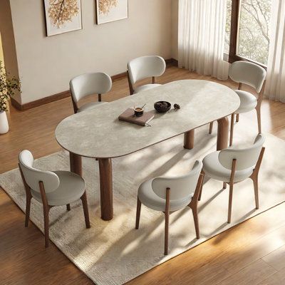 a dining room table with chairs and a rug on the floor in front of it