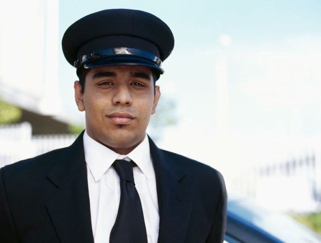 a man in a suit and tie standing next to a car wearing a police hat