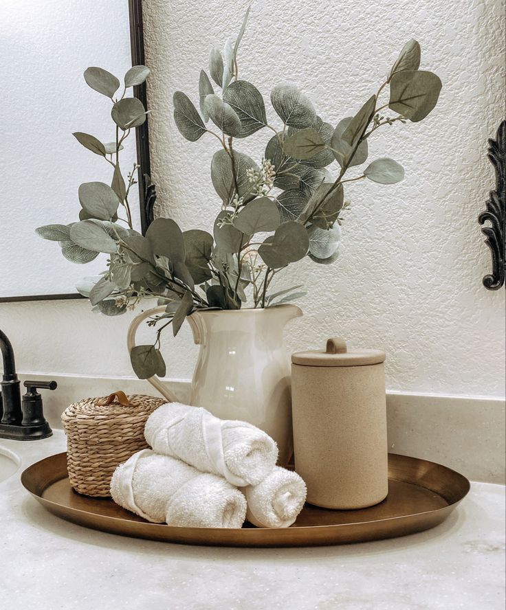 a bathroom sink with towels and a vase filled with greenery on top of it