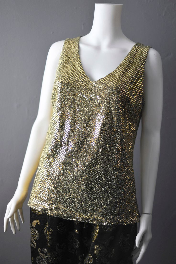 Simple sparkly gold sequin vest top from the early 2000s- pair with a black blazer for a glam evening look. Made from a metallic lurex type fabric, this has a bit of stretch to it but you might want to wear a cami under it if you have sensitive skin, as you might find it a little scratchy. No labels in this, but best fits up to a UK size 10 ( Bust=35 inches (88 cm) Waist=27 inches (68 cm) Hips=36 inches (93 cm) Garment Measurements; Bust= 38 inches (97 cm) Waist= 33 inches (84 cm) Hips= 37 inches (94 cm) Length shoulder to hem= 26 inches (66 cm) In great vintage condition, only flaw is some missing sequin dots in the armpits. Apologies for the terrible photos, I will try and add better ones! Affordable Gold Camisole Tank Top, Affordable Gold Stretch Tank Top, Metallic Tank Top For Party Season, Gold Sleeveless Sequin Fabric For Party Season, Gold Sequin Fabric For Party Season, Metallic Fitted Tank Top For Party, Glamorous Metallic Tank Top For Party Season, Glamorous Fitted Metallic Tank Top, Glamorous Fitted Shimmer Tank Top