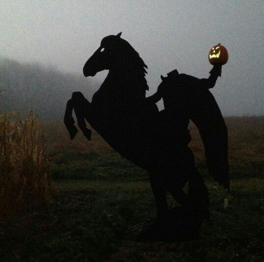 a silhouette of a horse with a pumpkin in its mouth and on it's hind legs