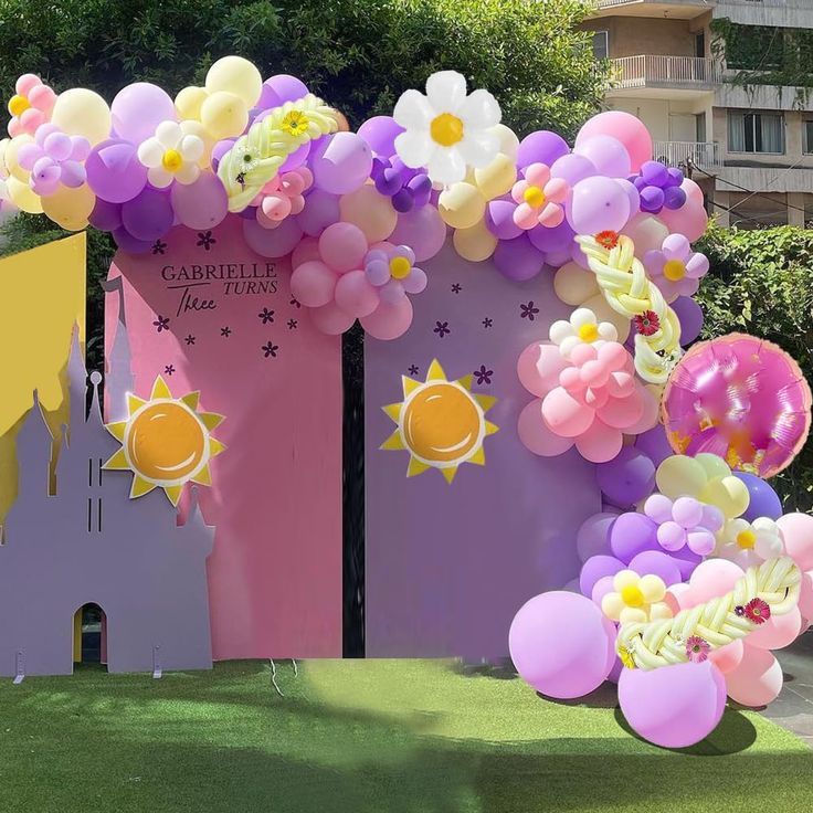 an arch decorated with balloons and flowers in front of a building