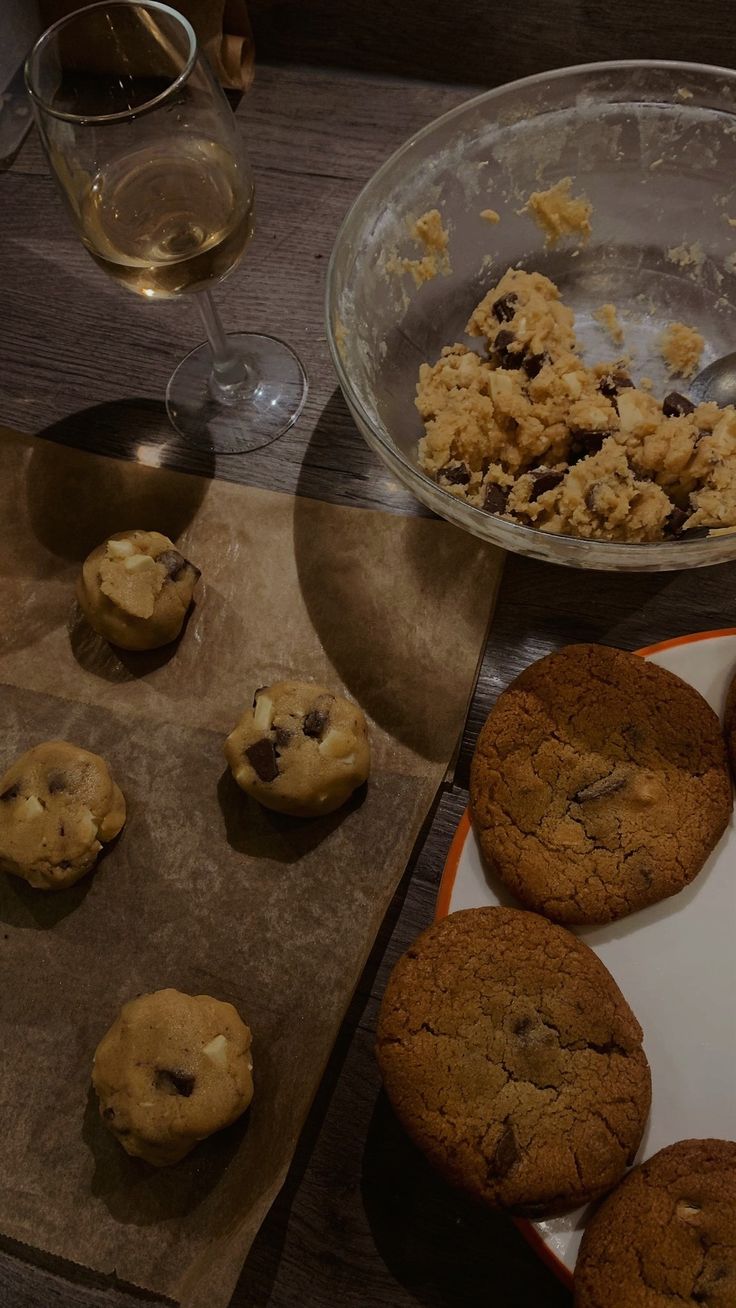 Fresh chocolate chip cookies on a plate, rolled up cookie dough balls on a baking sheet and a bowl of cookie dough, plus a glass of wine for the vibes Baking Chocolate Chip Cookies Aesthetic, Bake Night Aesthetic, Baking Date Night Aesthetic, Cookie Date Night, Baking Night Aesthetic, Late Night Baking Aesthetic, Night In Aesthetic Cozy, Baking At Night Aesthetic, Cosy Night In Aesthetic