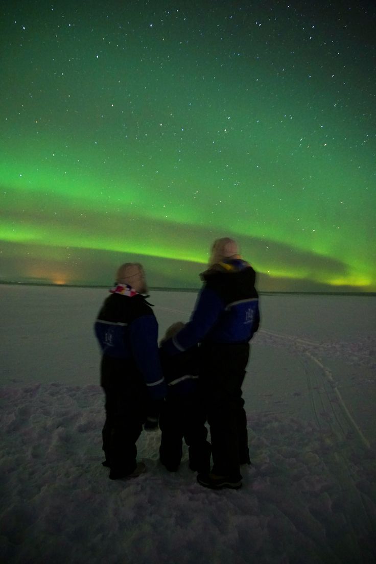 two people standing in the snow under an aurora bore