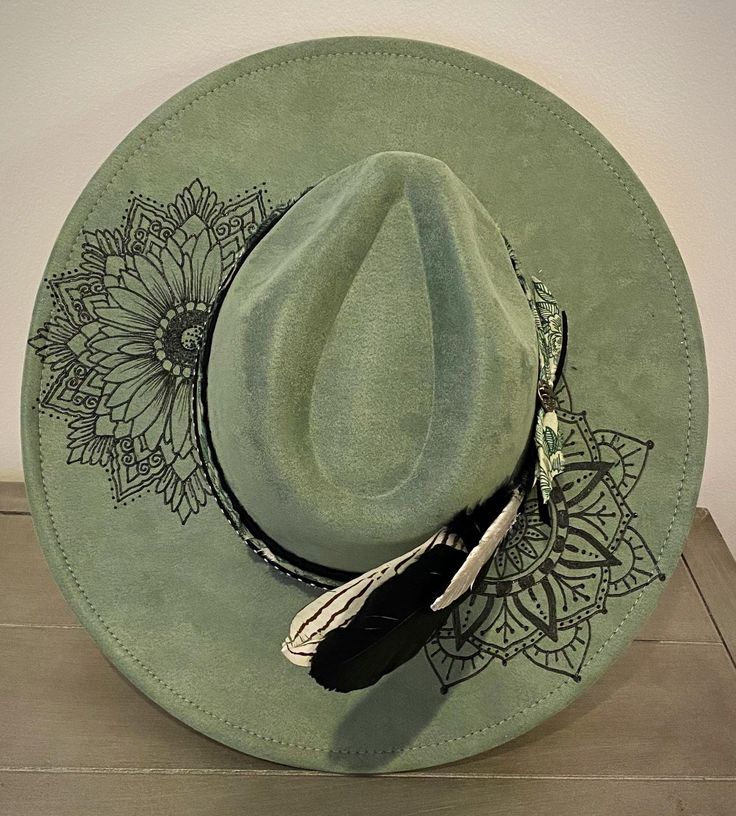 This sage green hat features mandala designs and a boho flair. Made from premium faux suede with cotton and leather banding. She has all the boho elements making her wild and bold! I use only the best materials for my hats and each one is handcrafted and uniquely one of a kind.  This hat has an adjuster inside the crown that allows 22-24.5 inch circumference; she fits most sizes. Brim length - 3.75" Height - 4.72" Due to the nature of my hats and because of various sanitary concerns, hats are NO Green Western Style Hat Band For Festivals, Western Green Hat Bands For Festival, Adjustable Green Hats For Festivals, Western Green Hat Band For Festivals, Adjustable Green Hat For Festivals, Adjustable Green Hat For Festival, Green Bohemian Hat Bands For Summer, Bohemian Green Hat Bands For Summer, Green Western Fedora For Summer