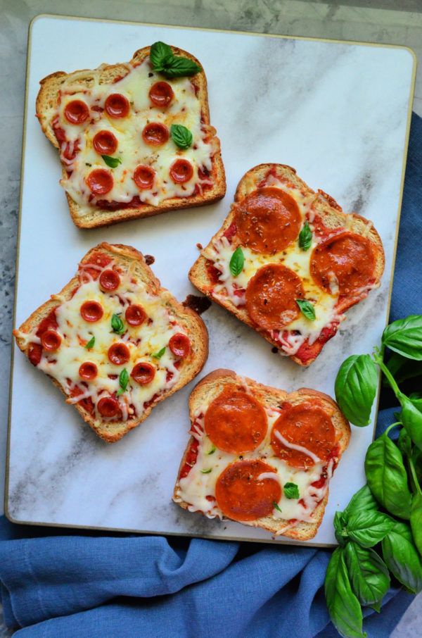 four slices of pizza on a plate with basil leaves and pepperoni in the middle