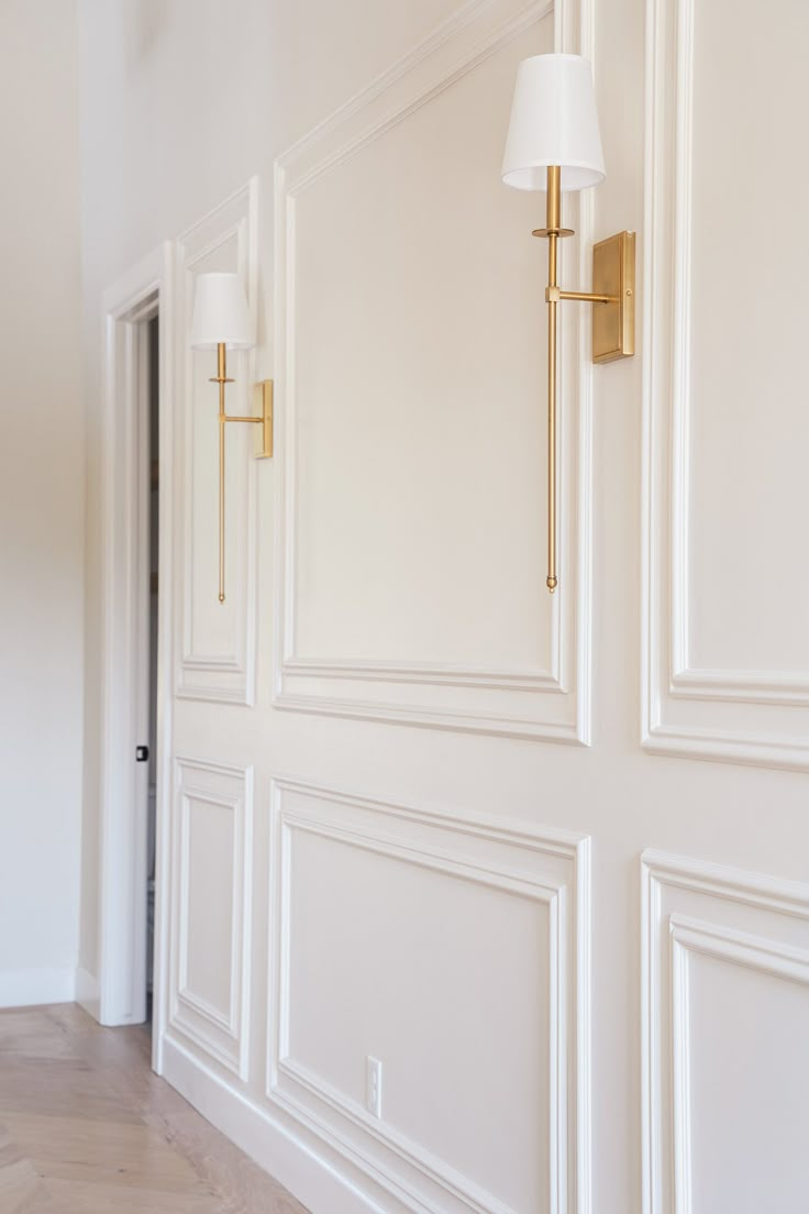 an empty room with white walls and gold trim on the door, light fixture and floor lamp