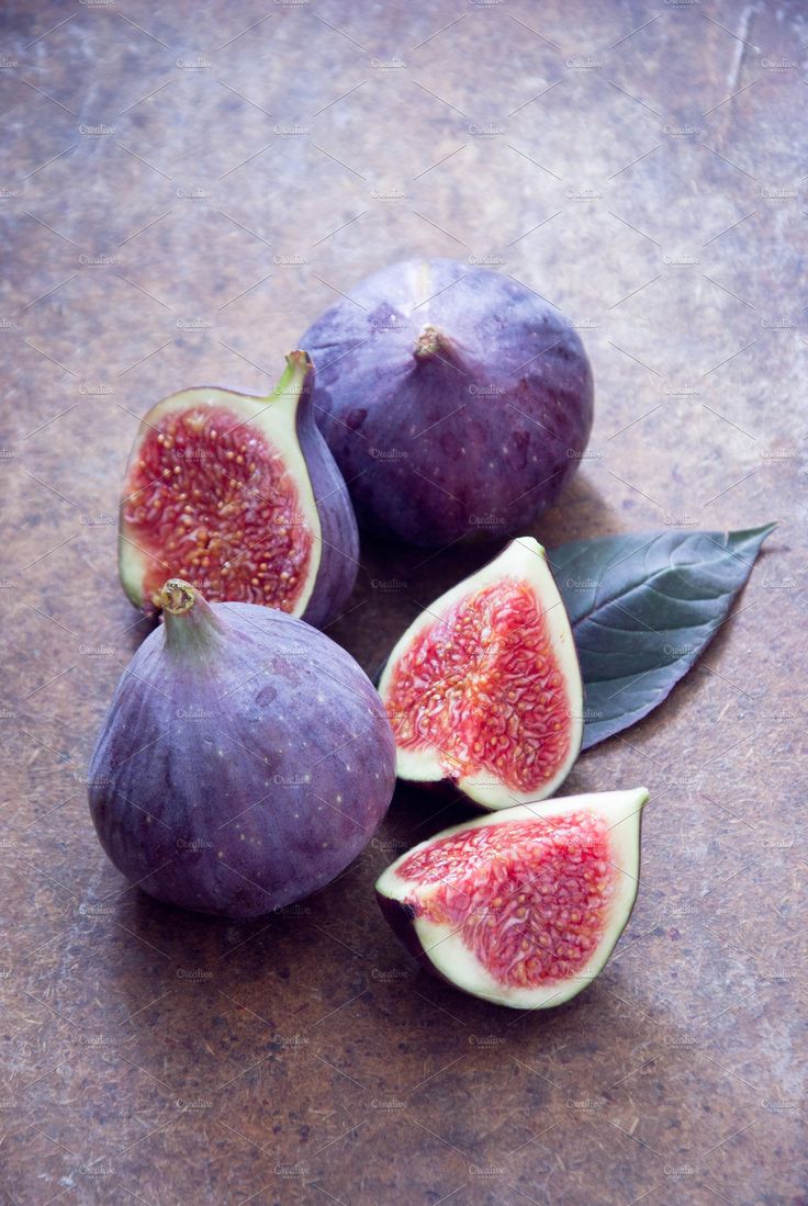 figs with leaves and one cut in half sitting on a counter top, ready to be eaten