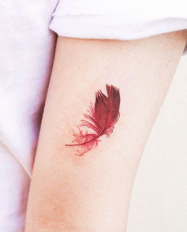 a small red feather tattoo on the arm