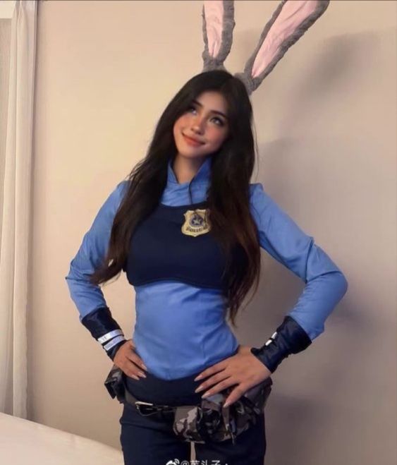 a woman in blue is standing next to a bed with bunny ears on her head