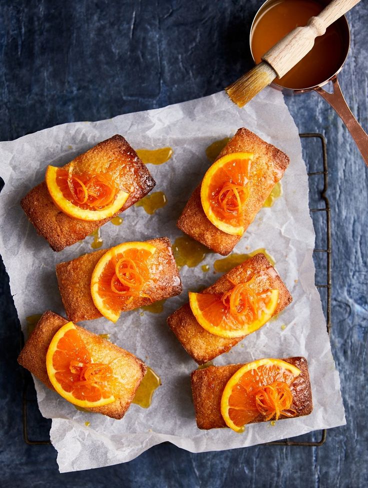 some oranges are cut in half and sitting on a piece of wax paper with honey