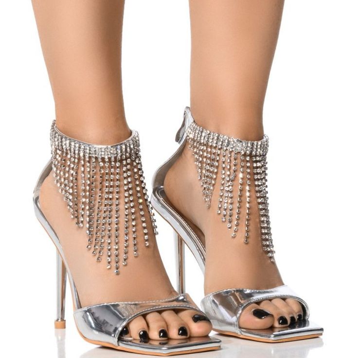 The Azalea Wang " Vanity Victoria " Embellished Stiletto Sandal In Silver Is Made From A Metallic Faux Leather Upper And Features An Open Square Toe Silhouette, A Cushioned Faux Leather Insole, An Ankle Strap With Rhinestone Fringe Trim, A Slim, Reflective Stiletto Heel, And A Back Ankle Zipper Closure. - Faux Leather Upper - Open Square Toe - Stiletto Heel - 4” Heel Height Ankle Strap Embellished Heels For Party Season, Embellished Ankle Strap Heels For Party Season, Formal Embellished Sandals For Party Season, Embellished Open Toe Sandals For Party Season, Party Season Embellished Open Toe Sandals, Embellished Heels For Gala And Party Season, Embellished Ankle Strap Sandals For Party Season, Glamorous Embellished Ankle Strap Heels, Rhinestone Embellished Open Heel Sandals For Cocktail