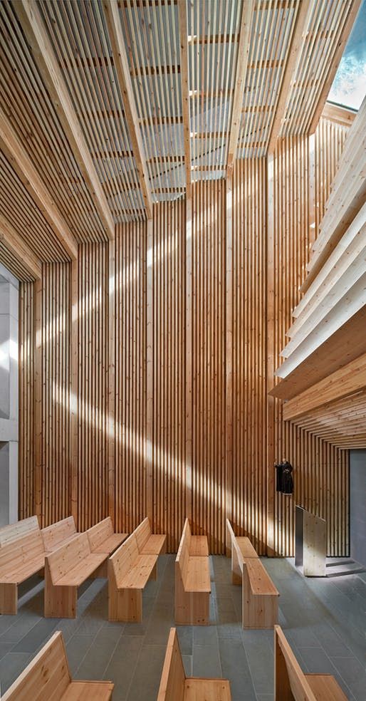 the interior of a building with wooden slats on the ceiling and benches in the center