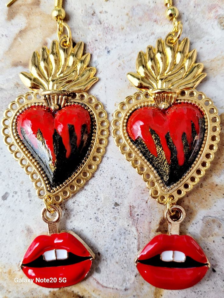 Beautiful and modern hand-painted sacred heart earrings, in Black and red, adorned with red lips, are protected with several layers of high-quality jewelry varnish, improving the quality and durability of the earrings. These hand-painted sacred heart earrings are unique and very beautiful, the ideal gift because they combine with any outfit both day and night, they will enhance the beauty and you will surely attract attention due to the unique and artisanal design, the Ideal gift for the Day of Mothers, weddings and holidays. Features/ Product info Note: The earrings in stock have some differences because they are hand painted. -The Main Material: Zinc Alloy (Gold) -Color: Black and red -Small: 1 in  (Please see the photos, this design comes in two sizes.) - Earrings: 3.25 in Including hoo Handmade Heart-shaped Enamel Earrings, Hand Painted Dangle Heart Earrings As Gift, Unique Hand Painted Heart Earrings, Hand Painted Heart Earrings For Valentine's Day Gift, Red Heart-shaped Hand Painted Jewelry, Hand-painted Red Jewelry For Valentine's Day, Hand Painted Red Jewelry For Valentine's Day, Artistic Hand Painted Jewelry For Valentine's Day, Unique Nickel-free Earrings For Valentine's Day