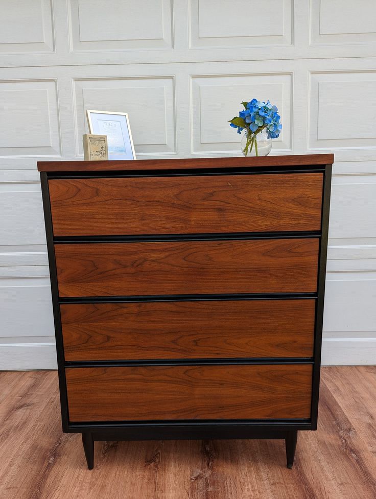 a wooden dresser sitting on top of a hard wood floor next to a white garage door