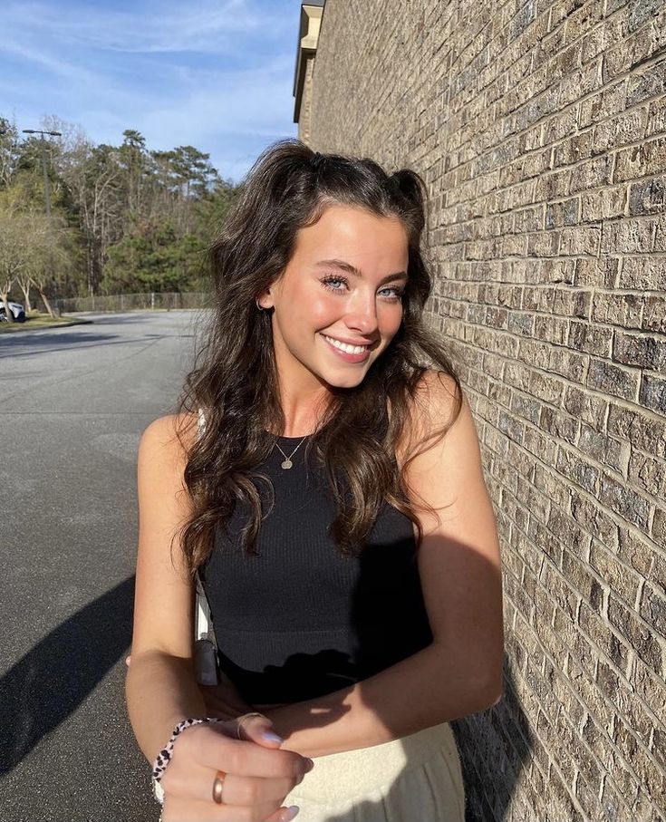 a woman standing next to a brick wall